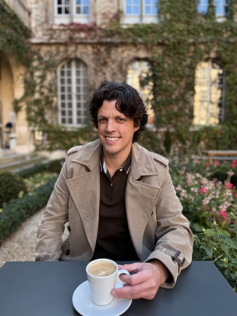 Photo of Graduate Nursing instructor Dr. Patrick Sherlock, sipping coffee in a garden