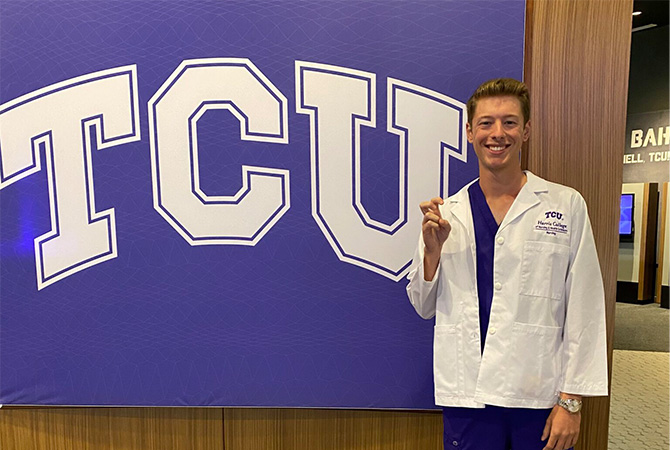 Garrett Harvill posing in front of a TCU banner